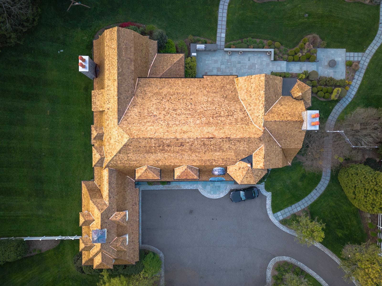 Aerial view of a cedar shake roof on a large home with a circular driveway
