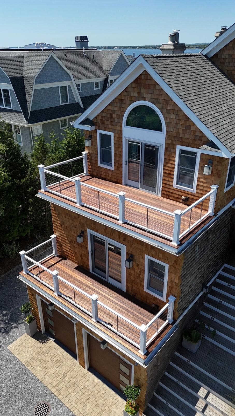 Coastal home with cedar shingle siding and white-railed balconies