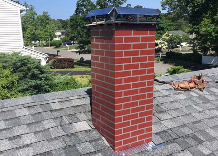 Rebuilt red brick chimney with a new metal cap