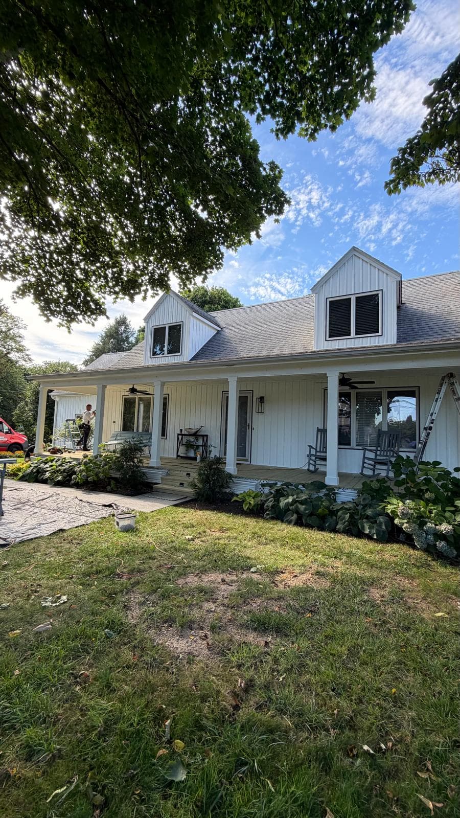 White farmhouse with board-and-batten siding, dormers and a covered front porch